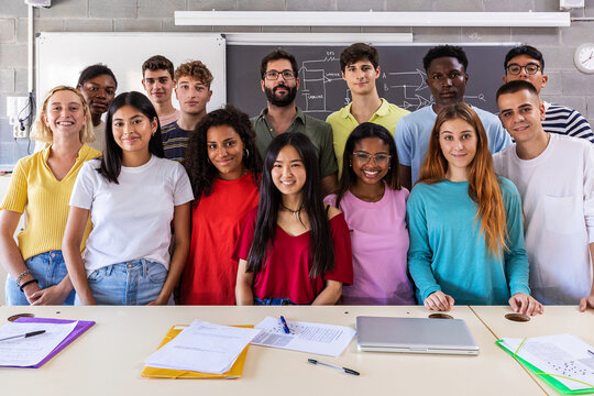 Portrait of smiling group of young multiracial students with teacher in class -