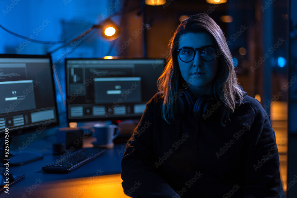 Poster cybercrime, hacking and technology concept - female hacker in dark room writing code or using comput
