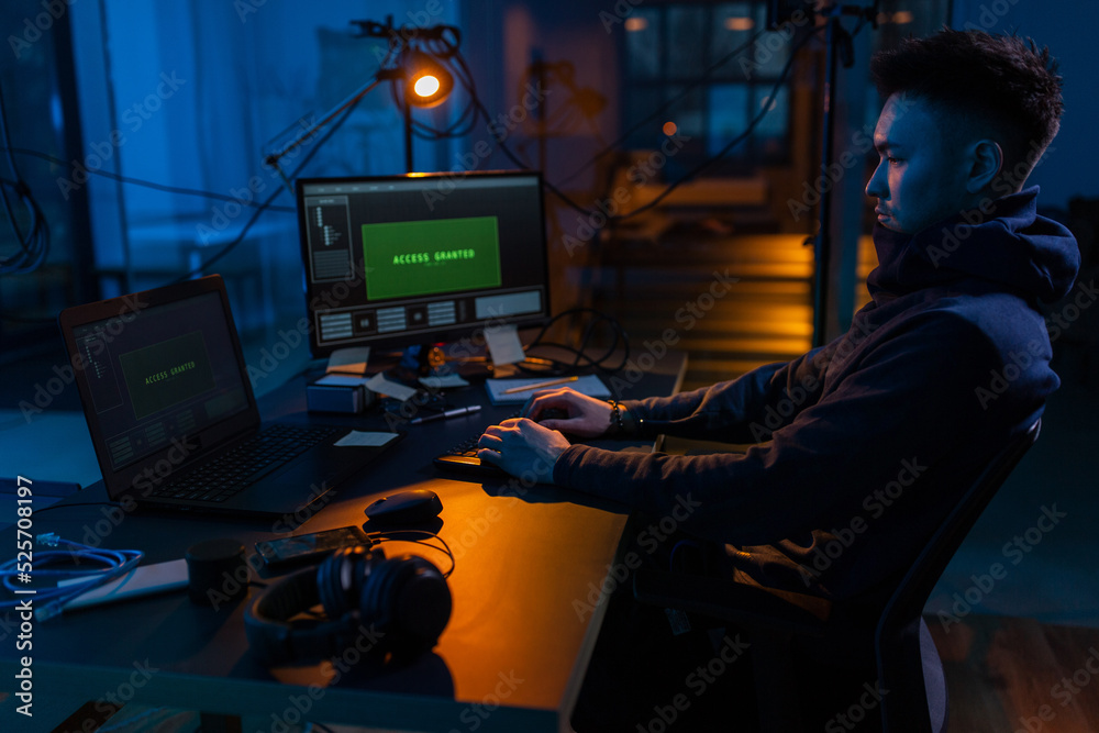 Poster cybercrime, hacking and technology concept - male hacker in dark room writing code or using computer