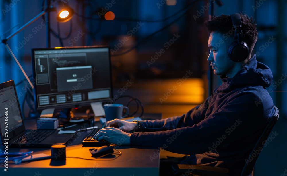 Poster cybercrime, hacking and technology concept - male hacker in dark room writing code or using computer