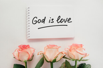 God is love - christian lettering, biblical phrase and pink rose flowers bouquet