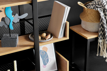 interior and home decor concept - close up of book shelf with art and decorations over black background