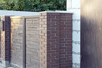brown wooden gate on a brick wall of a private fence in the street