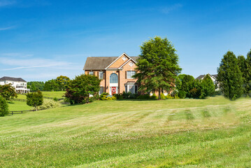 Landscape with a large country house. Large mowed lawn and blue sky.