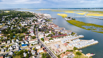Chincoteague Island, marinas, houses and motels with parking lots. bridge and road along the bay. Drone view.