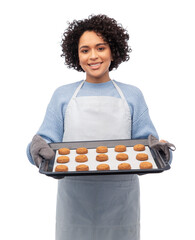 cooking, culinary and people concept - happy smiling woman in apron holding baking tray with...