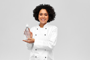 cooking, culinary and people concept - happy smiling female chef with hand sanitizer or liquid soap...