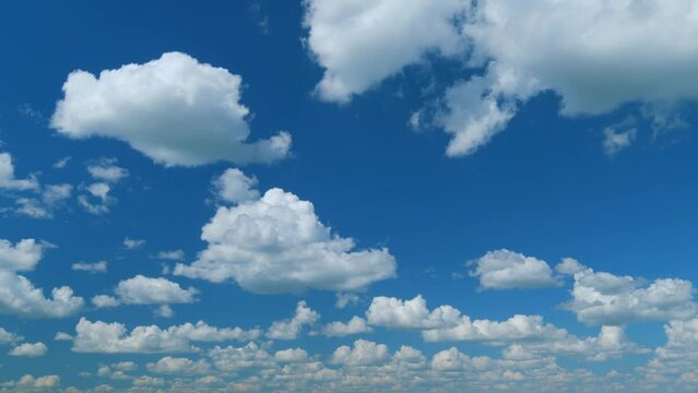 Clouds formation running across the blue sky. White puffy and fluffy layered clouds on blue sky. Time lapse.
