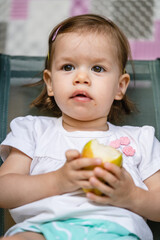 One girl small caucasian toddler child eat pear at outdoor copy space