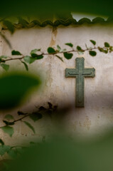 Cross Religion. Symbol. Worship. cross on worn wall among vegetation, plant out of focus and tiles on the top, mexico