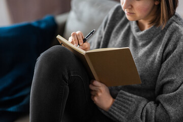 people, leisure and depression concept - close up of sad woman with diary sitting on sofa at home