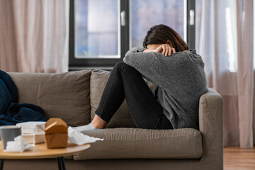 mental health, psychological problem and depression concept - stressed woman sitting on sofa at home