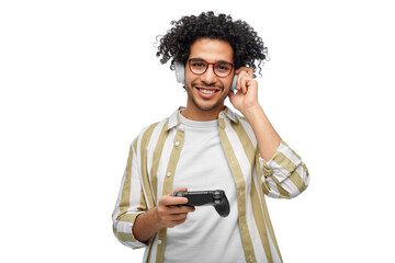 technology, people and leisure concept - happy smiling young man in headphones with gamepad playing video game over white background © Syda Productions