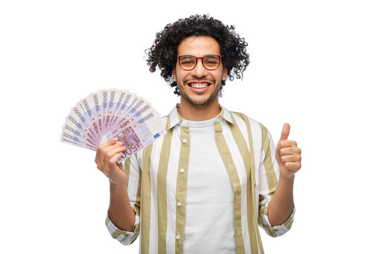 finance, currency and people concept - happy man holding hundreds of euro money banknotes showing thumbs up over white background