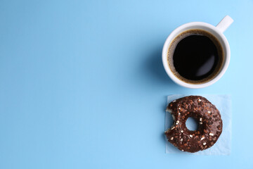 Tasty donut and cup of coffee on light blue background, flat lay. Space for text