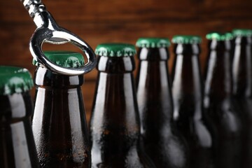 Opening bottle of beer on wooden background, closeup. Space for text