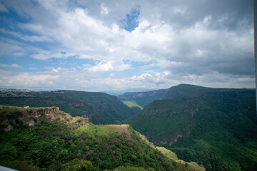 ravine trees and vegetation, view of several mountains at different depths, blue sky and few clouds, mexico