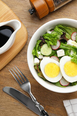 Delicious salad with boiled egg, feta cheese and vegetables served on wooden table, flat lay