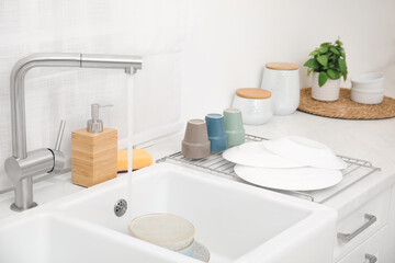 Drying rack with clean dishes near sink in stylish kitchen