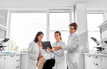 Fototapeta premium science research, work and people concept - international team of scientists with tablet pc computer working in laboratory