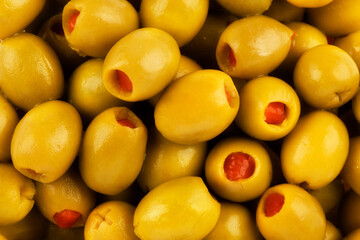 Salted green olives stuffed with red pepper as background. Really close up.