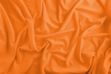 Orange textile background with wrinkles and waves