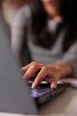 Young adult typing information on laptop, searching report and sending professional email. Using computer to search online data and browse internet network, taking notes and learning. Close up.