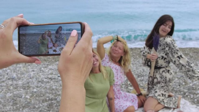 Four women taking pictures during a picnic on the beach