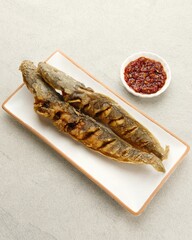 Lele Goreng, Fried Catfish is Indonesian traditional culinary food. served on white plate with chilli tomato paste (sambal)