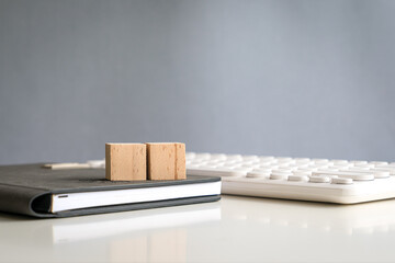 Two blank wooden block cubes in a row on top of a notepad next to keyboard. Free text and for business template.