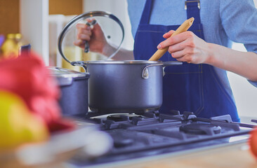 Cooking woman in kitchen with wooden spoon