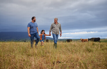 Farmer family walking on a cattle or livestock farm teaching and learning together. Generations of...
