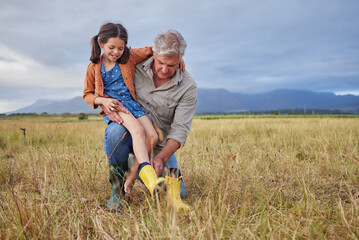 Naklejka na ściany i meble Happy family bonding on farm grandparent and girl having fun in nature, prepare for walk together. Smiling child and caring grandfather exploring outdoors, enjoying a walk in the countryside or field