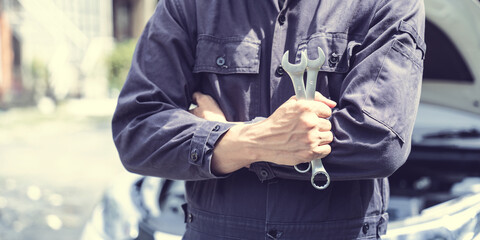 Crossed hands and holding wrench, Car mechanical engineering working at workshop garage.