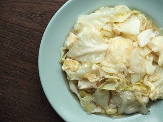 Top view dish of stir fried cabbage with fish sauce on wooden background