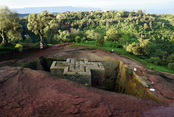 Top down view of the rock-hewn Church of Saint George in Lalibela in the early morning with a number of white-robed worshipers around its edges - obrazy, fototapety, plakaty