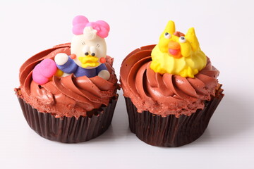 A colorful cupcake with doll on top , isolated