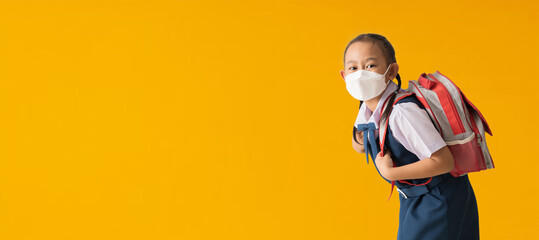 Asian schoolgirl in uniform wear medical face mask, isolated on yellow background with Clipping paths for design work empty free space