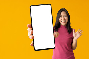 Obraz premium Happy asian woman holding big smartphone on yellow background, isolated Clipping paths for design work empty free space mock up product display presentation.