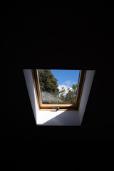 Closed roof window skylight. View of the sky and trees from the window.
