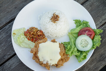 Chicken parmigiana mozzarella with rice and vegetable on a white plate, served with salad. italian cuisine indonesian version