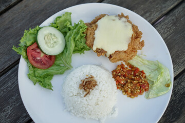 Chicken parmigiana mozzarella with rice and vegetable on a white plate, served with salad. italian cuisine indonesian version