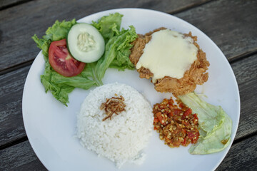 Chicken parmigiana mozzarella with rice and vegetable on a white plate, served with salad. italian cuisine indonesian version