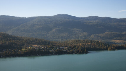 Fototapeta premium Scenic View of Kalamalka Lake and a small City during sunny summer sunrise. Vernon, British Columbia, Canada. Panorama