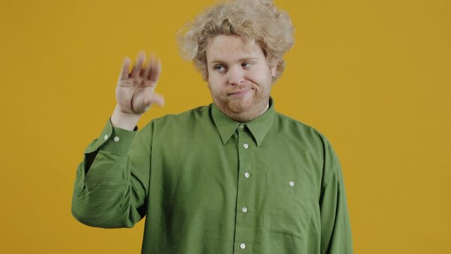 Portrait of annoyed person making bla bla bla hand gesture and moving mouth standing on yellow background expressing negative emotions