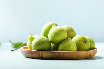 Fresh ripe figs in a plate wooden on lught blue background.