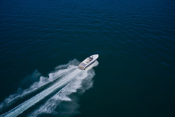 Large high speed yacht fast moving diagonal air view. A white boat with a man is moving fast on...