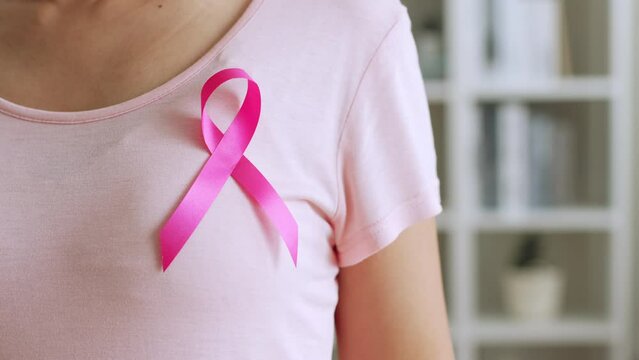 Woman show pink ribbon as sign of October Breast Cancer Awareness month
