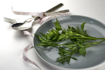 a plate of greens wrapped with a measuring tape next to a fork and spoon the concept of vegetarianism veganism diet