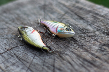 2 fishing vibrating lures for catching predatory fish, laid out on a wooden base